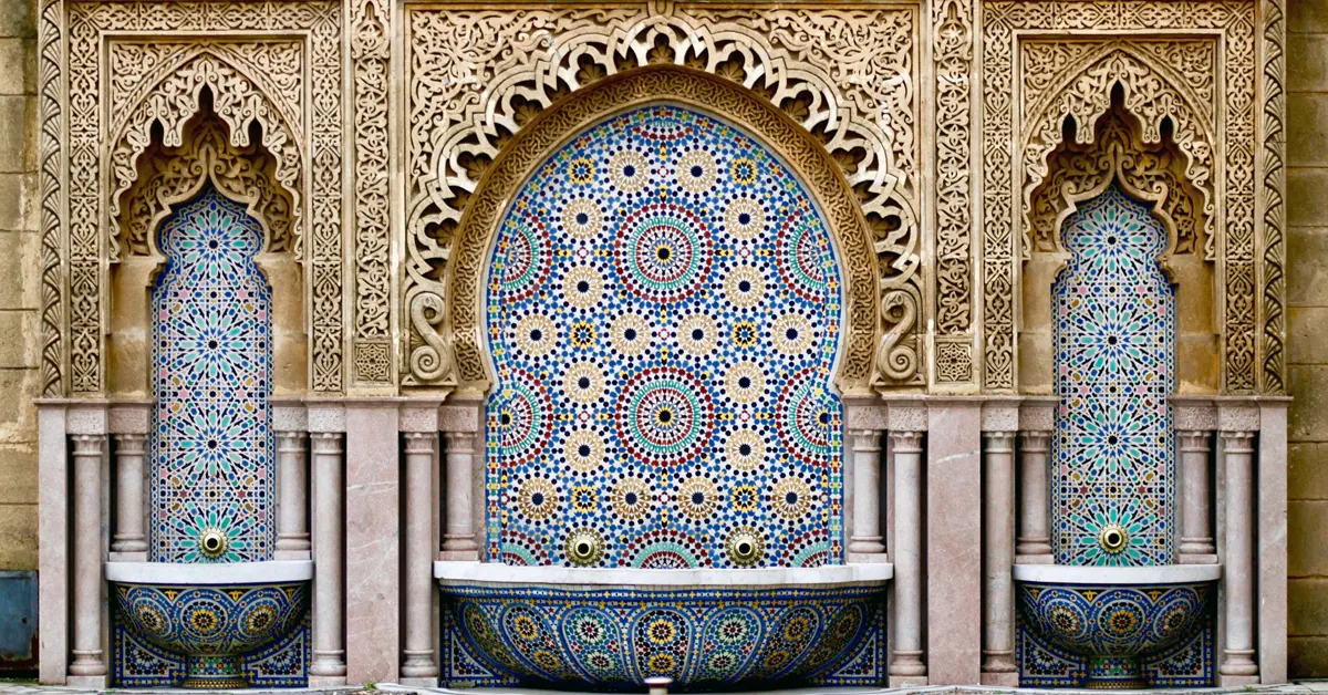 Intricate traditional Moroccan zellij tile fountain with carved plaster arches in Rabat, Morocco.