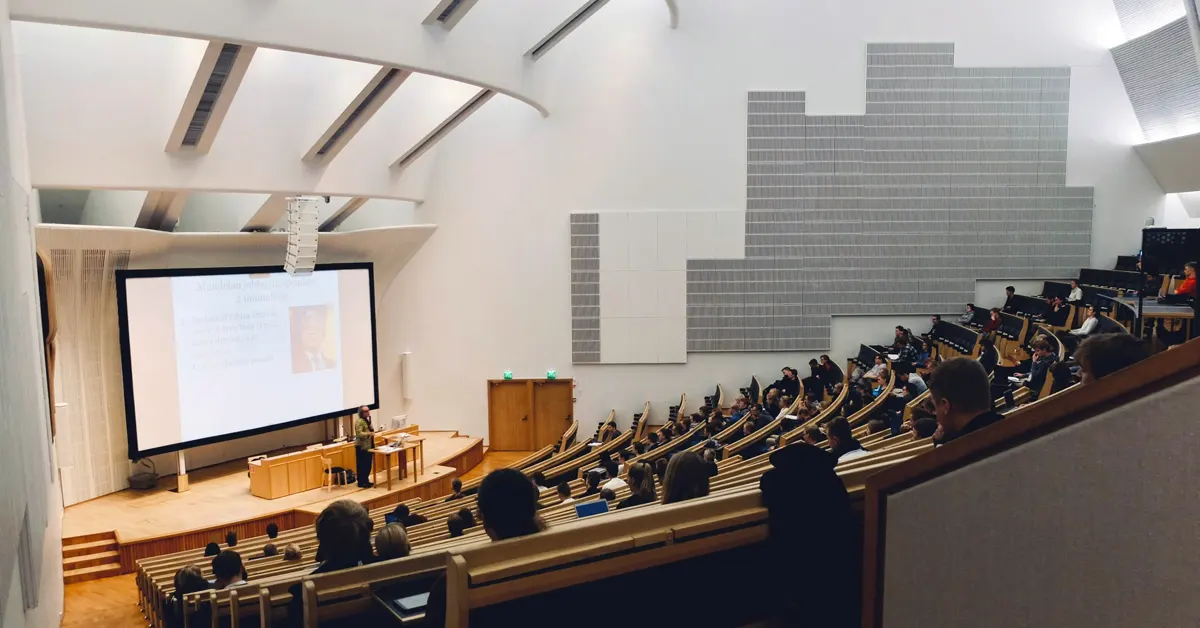 Sparse crowd of students listening to a presentation inside a large university lecture hall