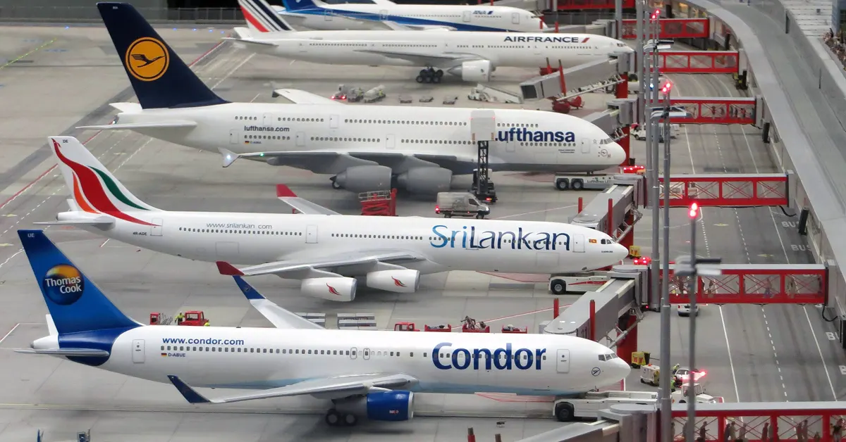 Miniature model airplanes including Condor, SriLankan Airlines, Lufthansa, and Air France parked at airport gates.